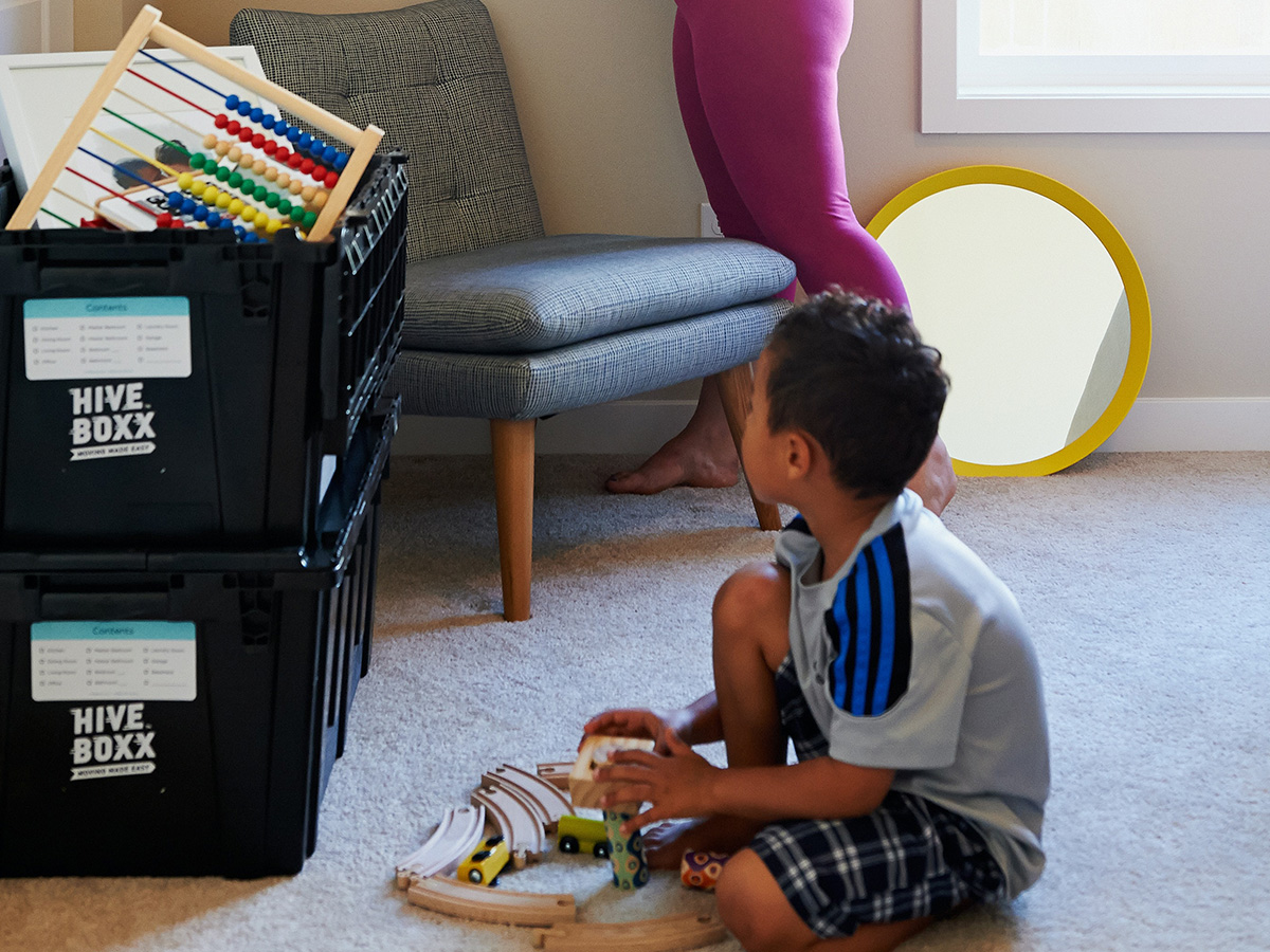 son on floor next to moving box